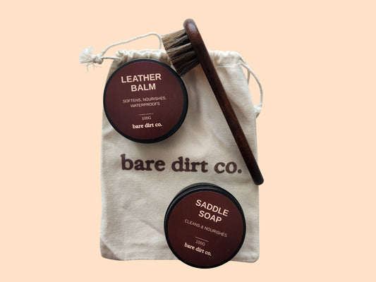Top view of The Foundation glove care kit consisting of leather balm, saddle soap, soft brush and drawstring storage pouch
